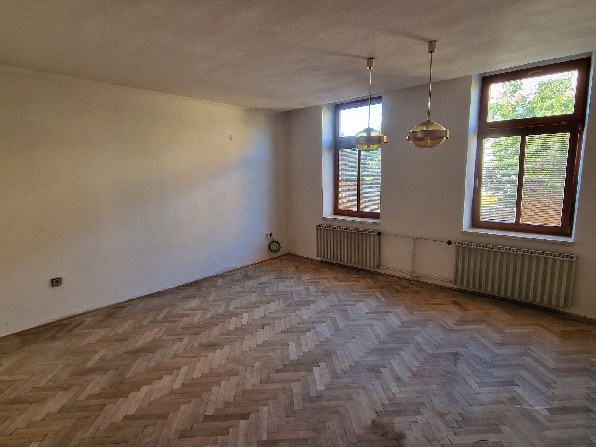 Obývací pokoj s parketami a okny do ulice